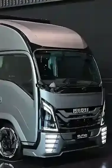 Silver Isuzu box truck with a high roof, shown front view indoors under dark lighting