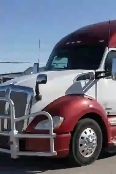 Red and white semi-truck parked outdoors under a clear blue sky.