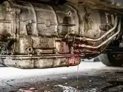 Undercarriage of a vehicle with a visible oil leak dripping onto the ground