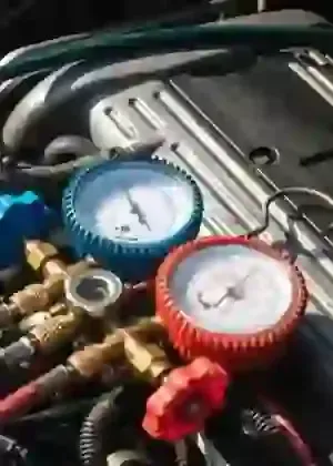 Colorful gauges and valves on HVAC refrigerant manifold tools, with blue and red dials.