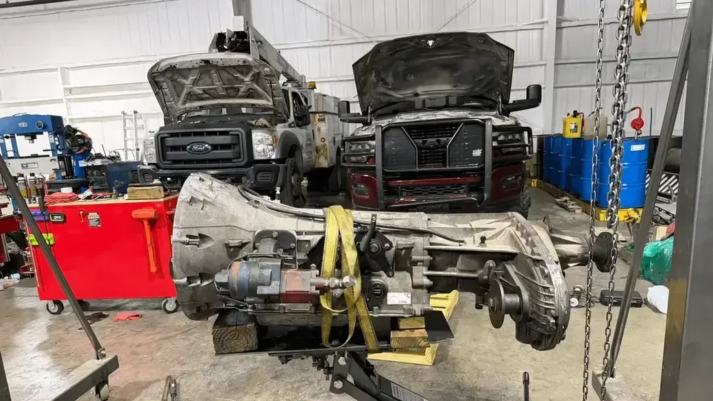 Semi-truck with hood open after roadside breakdown, exposing engine on a wet road.
