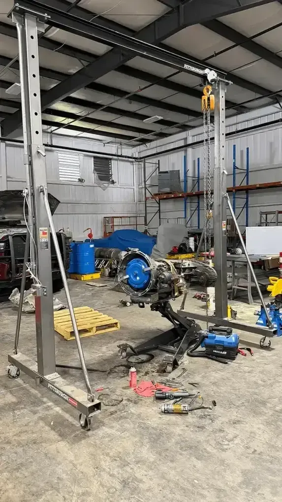 Person using a long tool to work under a vehicle in a garage