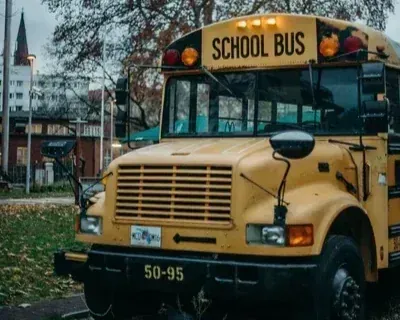 Yellow school bus parked on a street with trees and buildings in the background