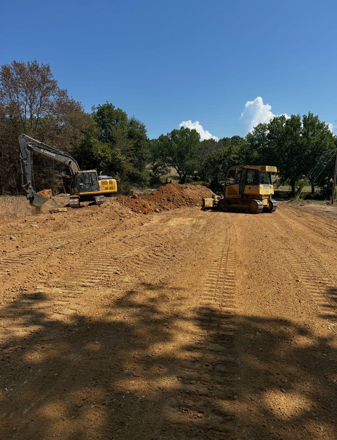Construction site with two yellow excavators on a dirt lot under a blue sky