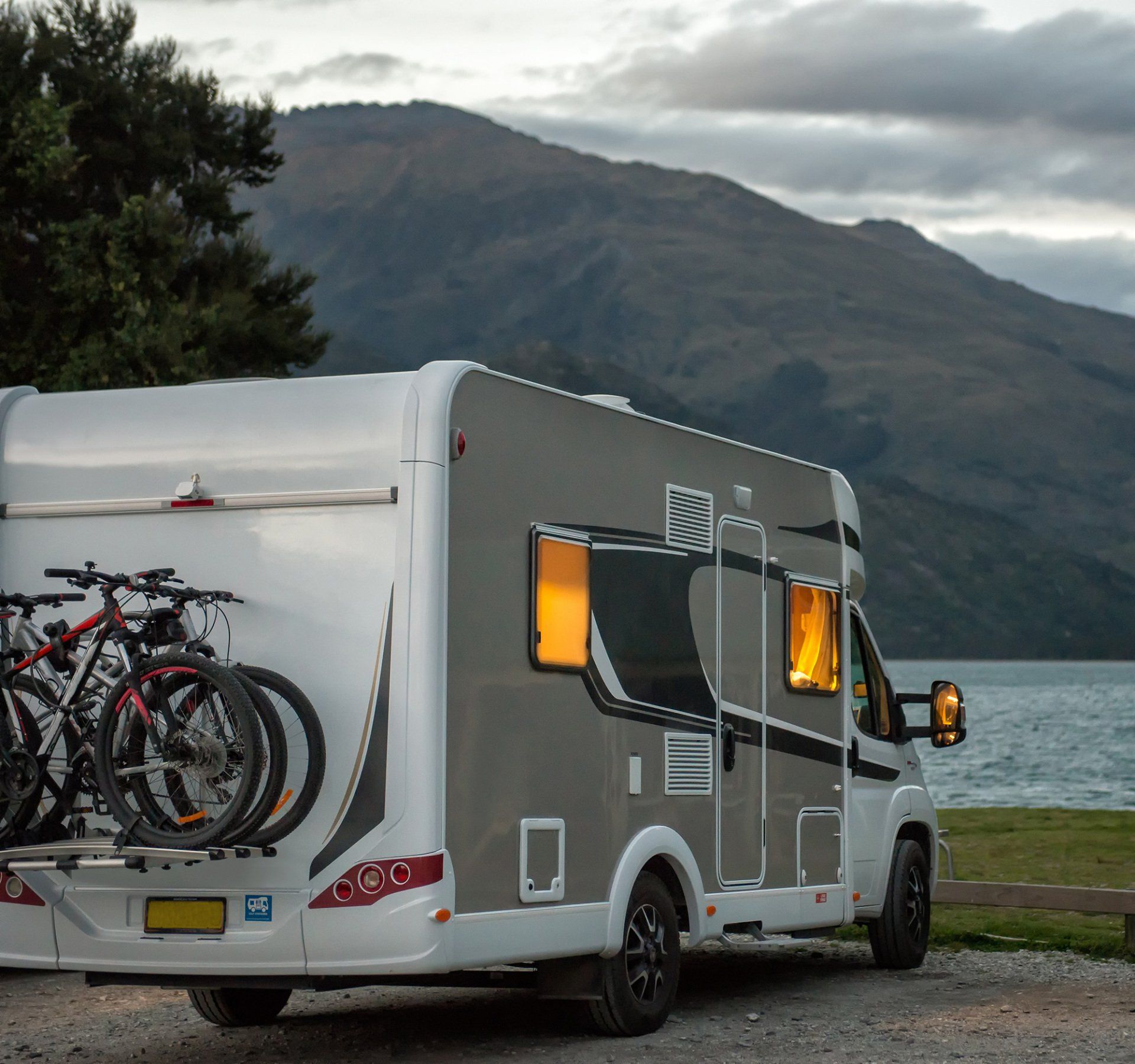 European style motorhome with interior lights on, parked at dusk at the Boundary Creek Campsite