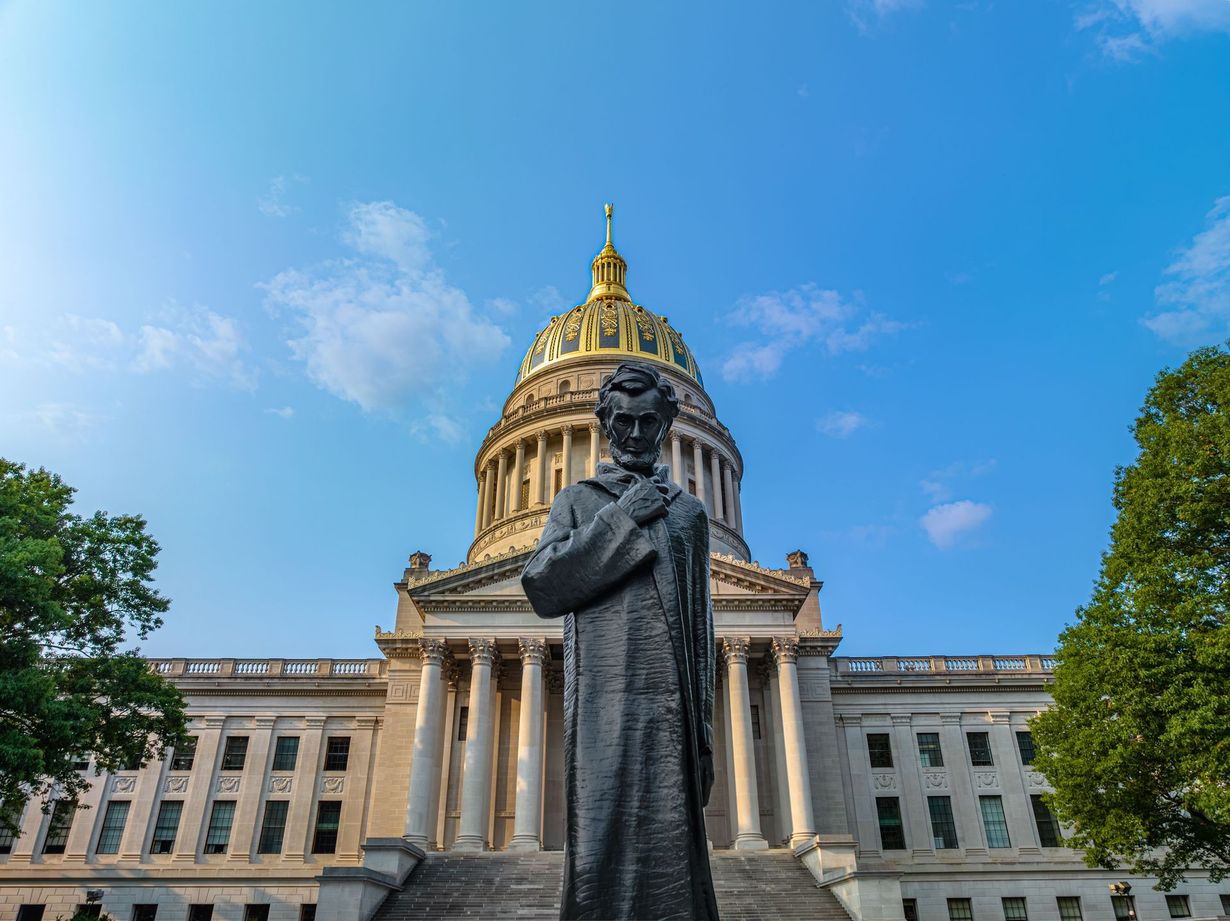 Statue before the U.S. Capitol dome on a sunny day with blue sky