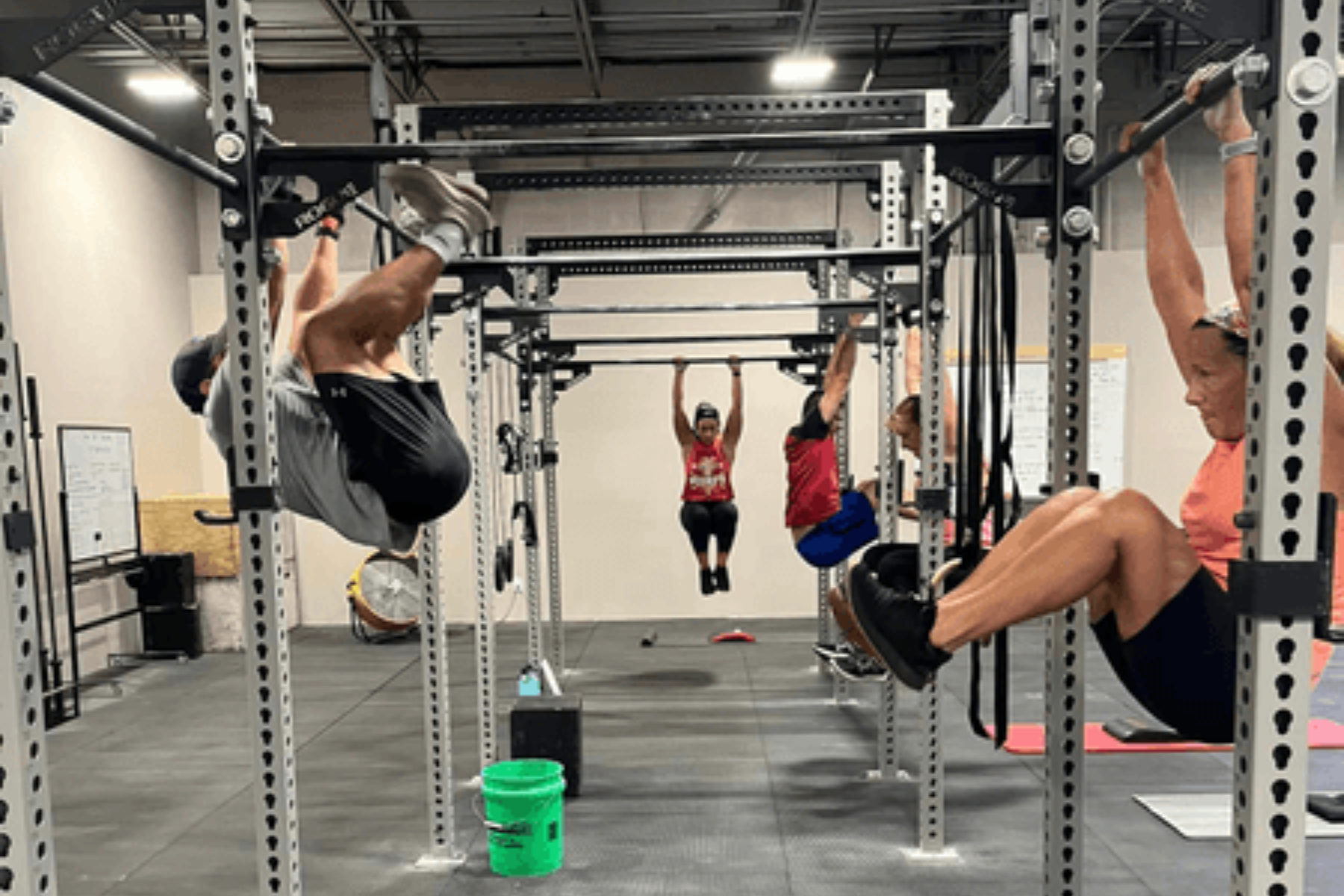 A group of people are doing pull ups on bars in a gym.