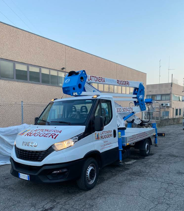 Camion bianco di servizio con piattaforma aerea blu parcheggiato fuori da un edificio industriale