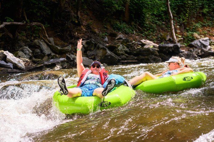 A man and a woman are tubing down a river.