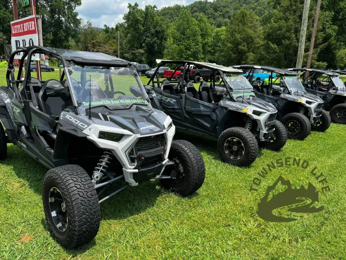 A row of atvs are parked in a grassy field.