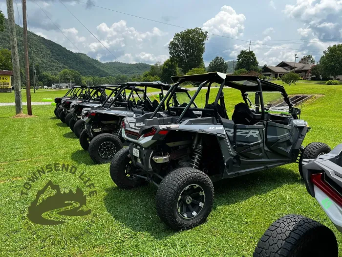A row of atvs are parked in a grassy field.