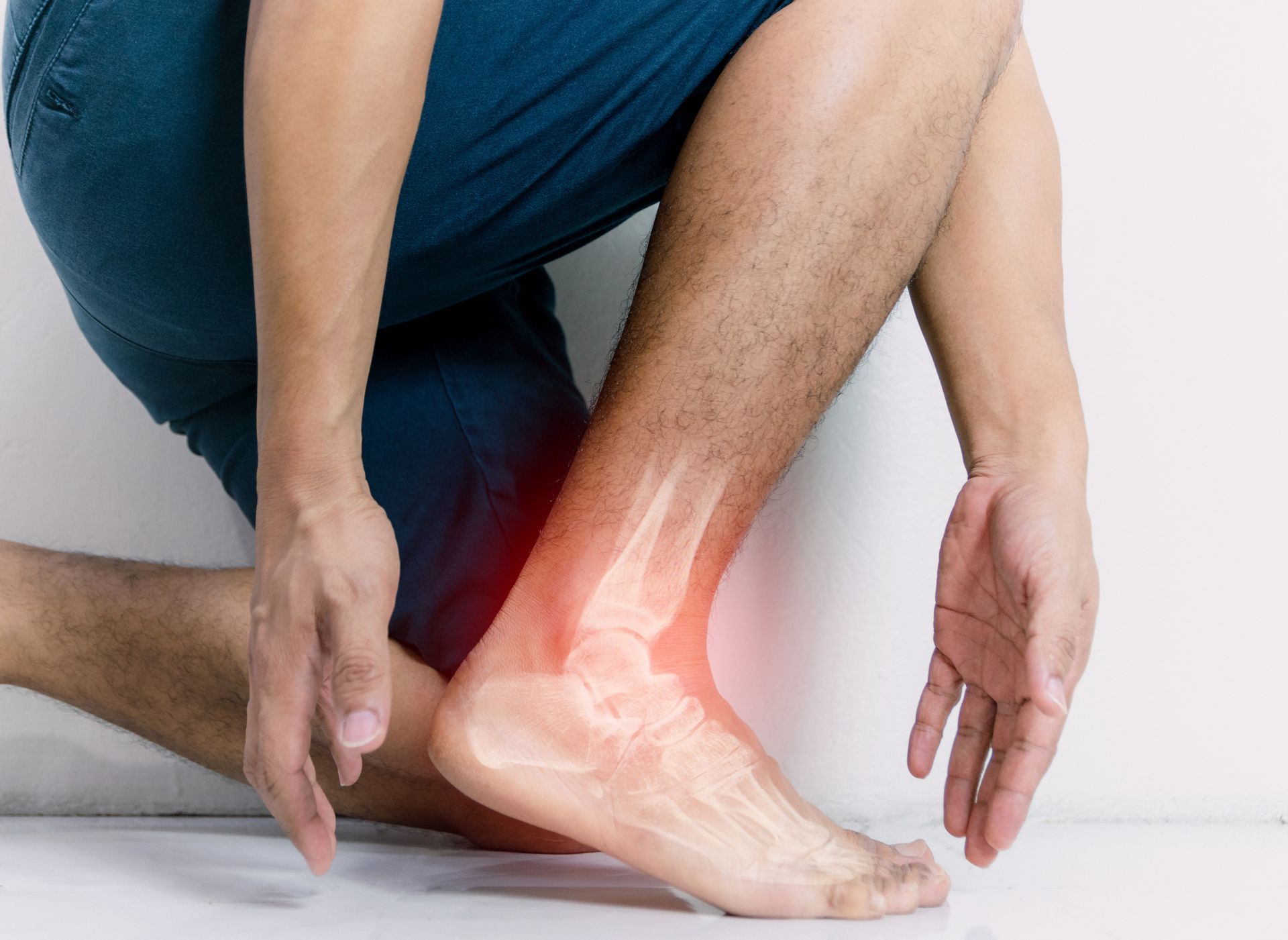 Ankle with highlighted pain area as a person holds their injured foot.