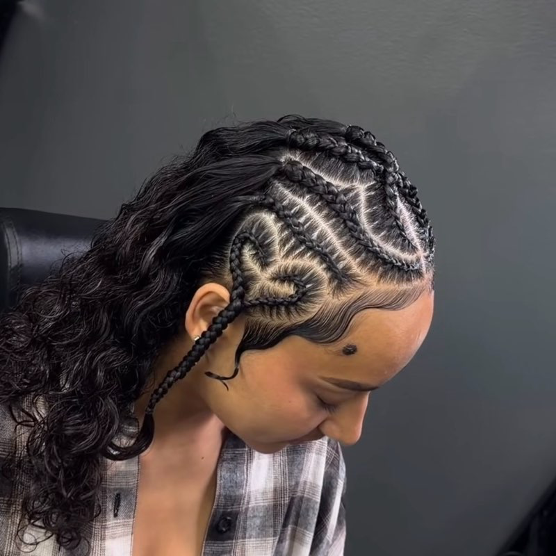 Braided hairstyle with curly hair. Braids curve across the head forming a heart. A person's profile is visible.