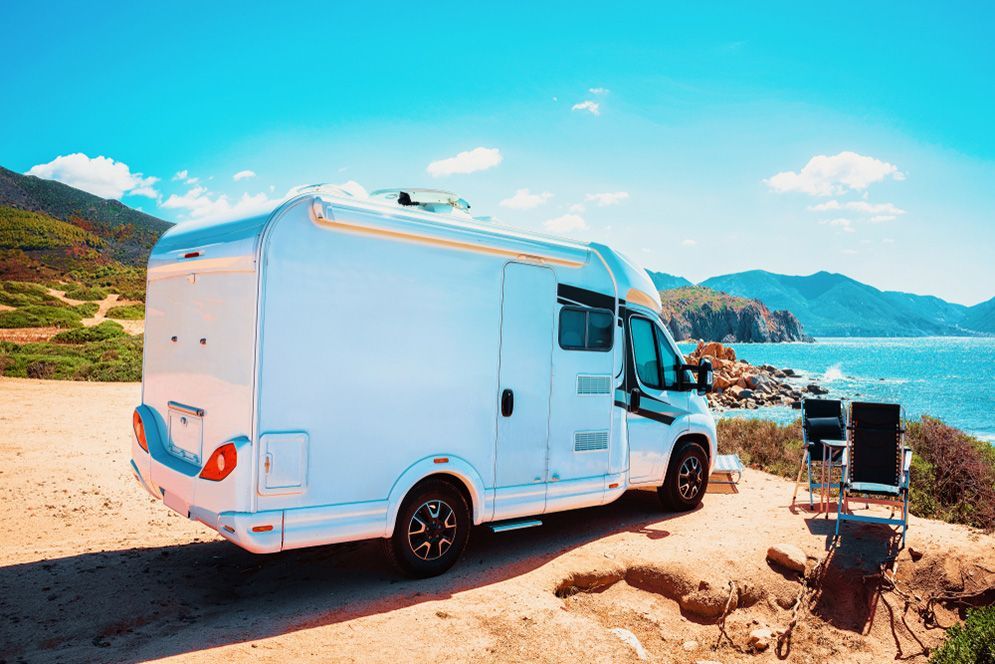 A White Rv Is Parked On A Dirt Road Next To The Ocean — Total Auto Service In Caloundra West, QLD