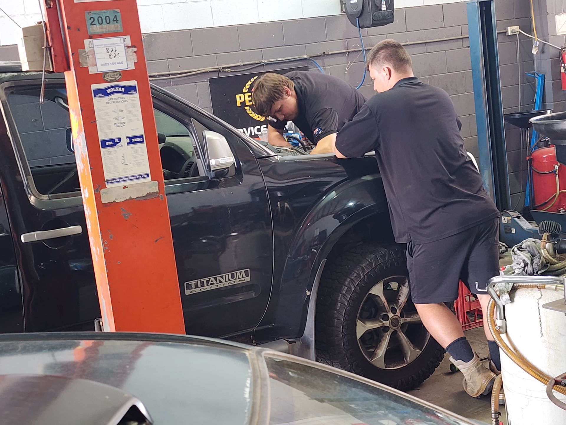 Two Mechanics Working on a Black Pickup — Total Auto Service In Caloundra West, QLD