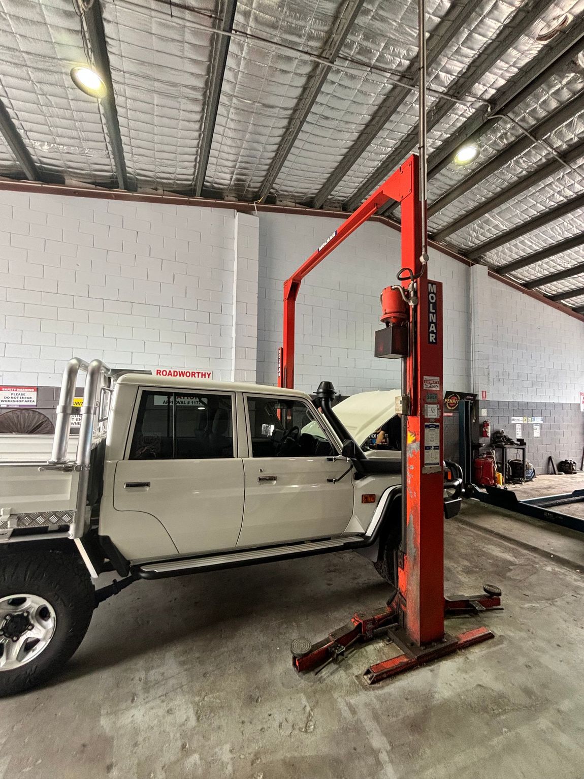 White Ute on a Lift in a Repair Shop — Total Auto Service In Caloundra West, QLD