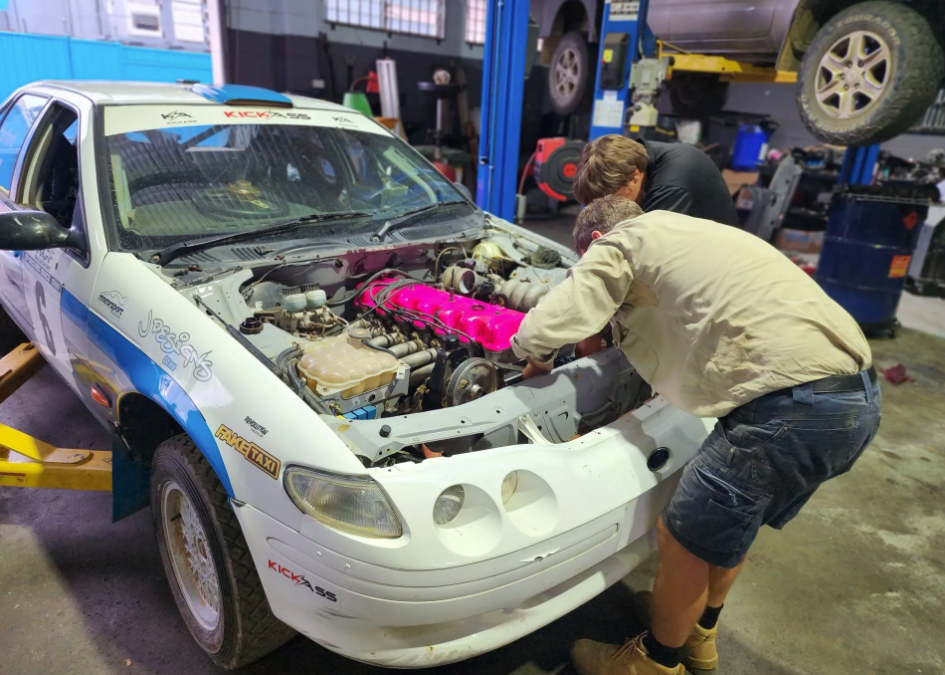 Mechanics servicing a car's engine in an automotive workshop