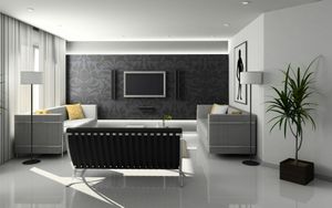 A modern living room with a black patterned feature wall, a wall-mounted TV, two grey sofas, and a potted plant.