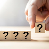 Hand placing a question-mark block above a row of question-mark blocks on a light background