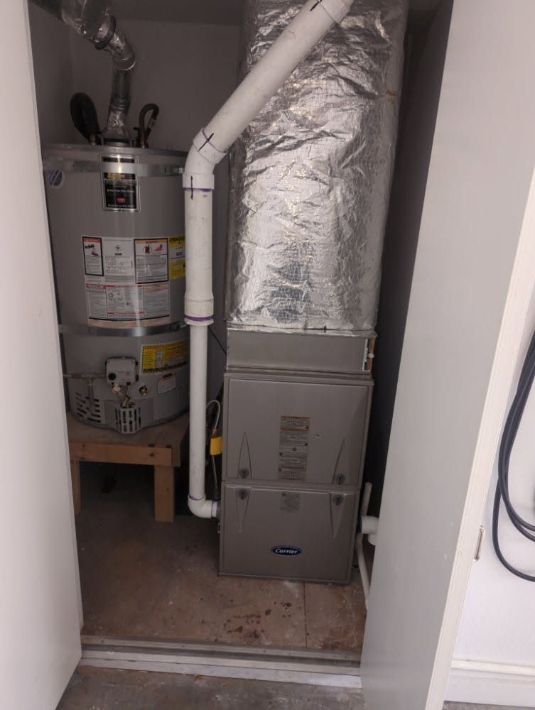 Closet utility area with a water heater, furnace, and exposed ducts/pipes.
