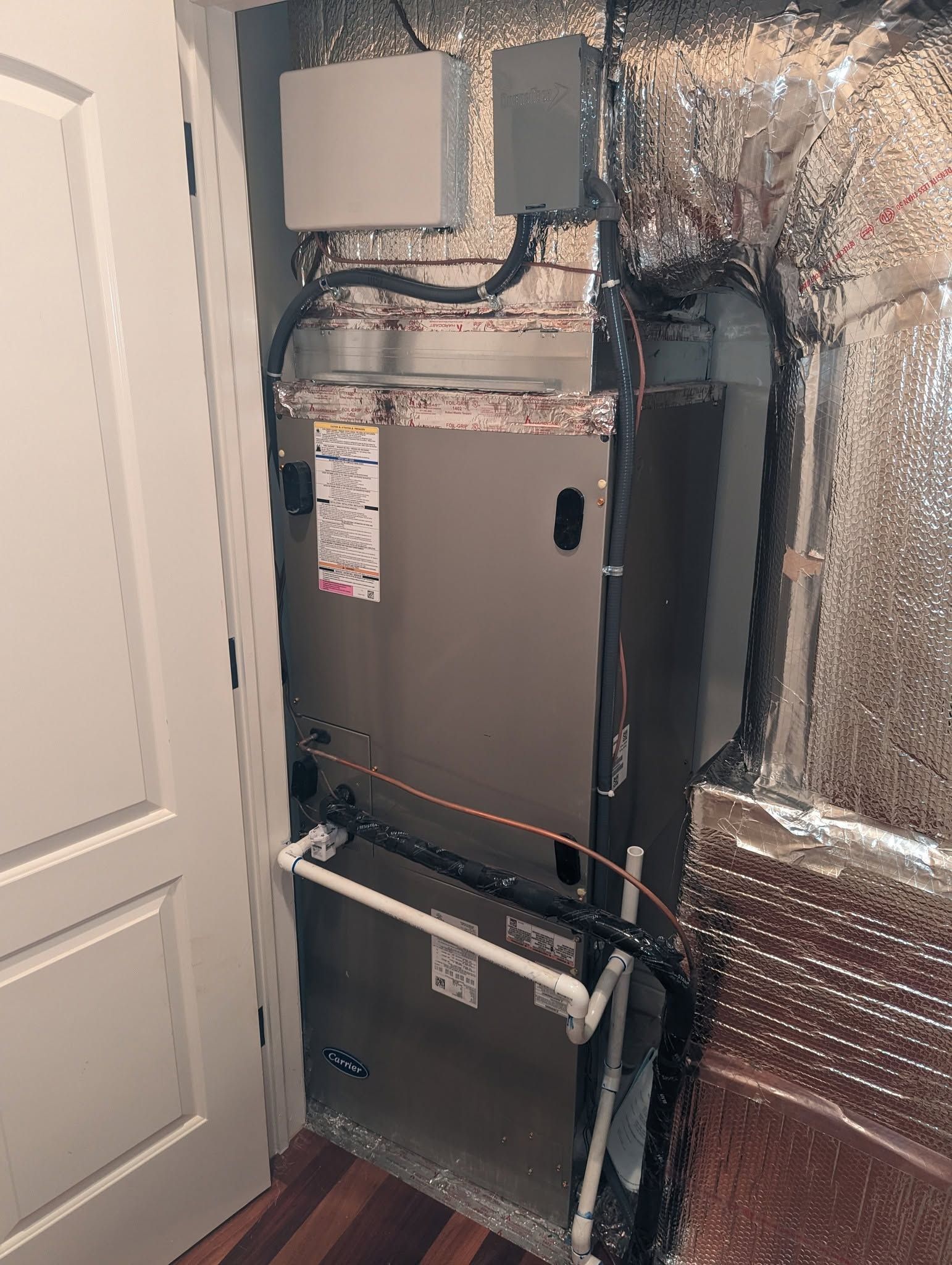 HVAC furnace and ductwork in a utility closet with reflective insulation