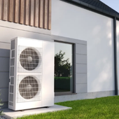 Outdoor heat pump unit beside a modern house wall and window, on a concrete pad by green grass
