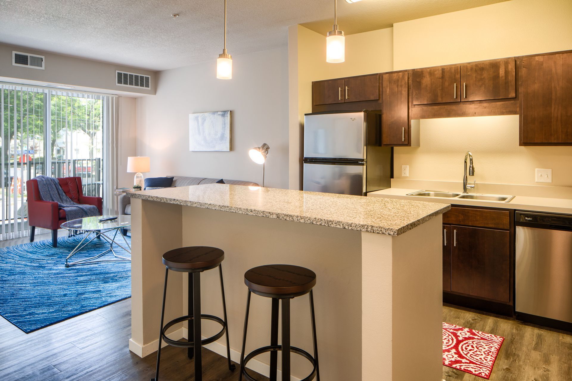 Open-concept apartment with kitchen, breakfast bar, and living room visible through a sliding glass door.