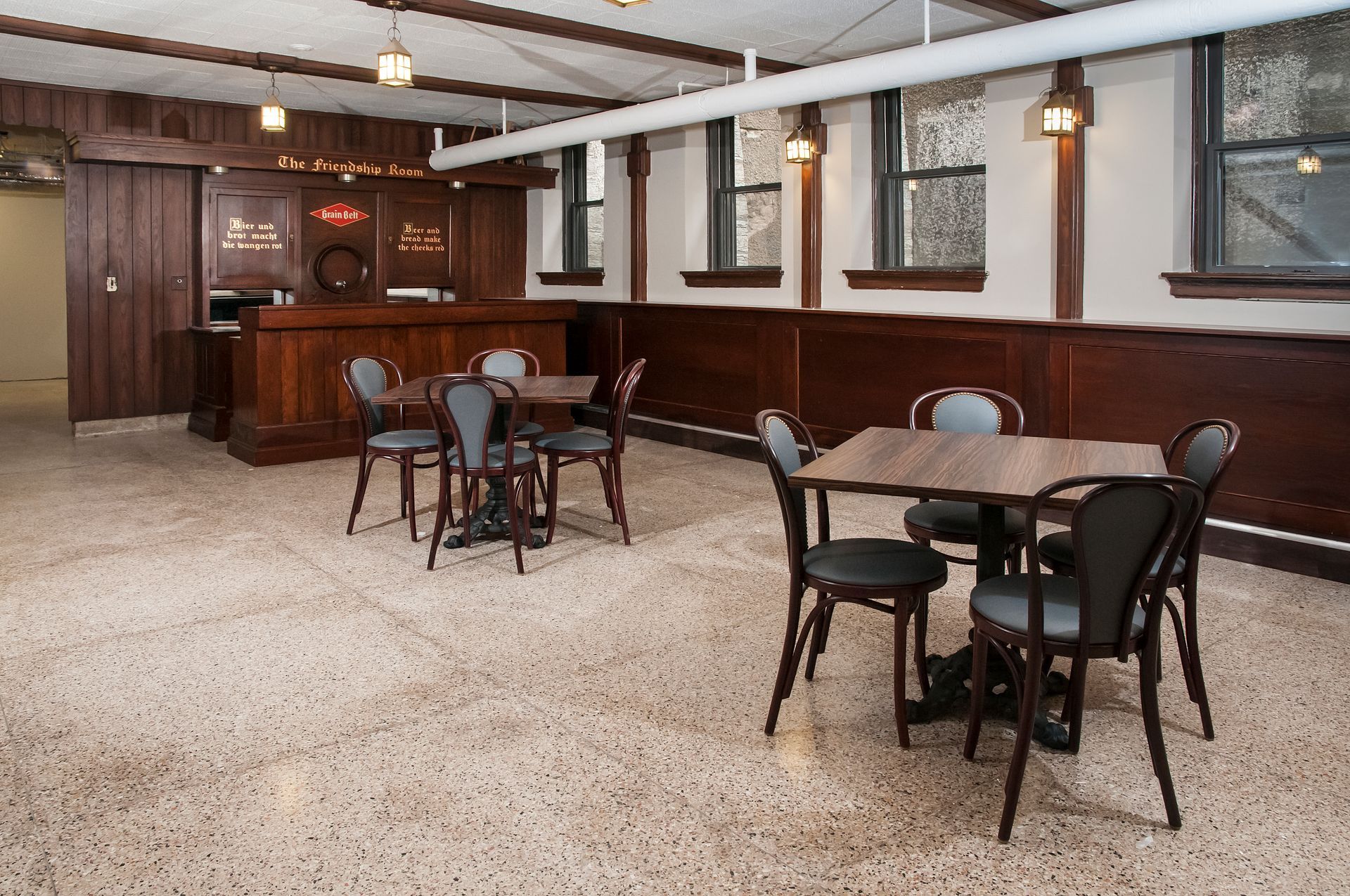 Interior bar area with wood bar, tables, chairs, and speckled floor.