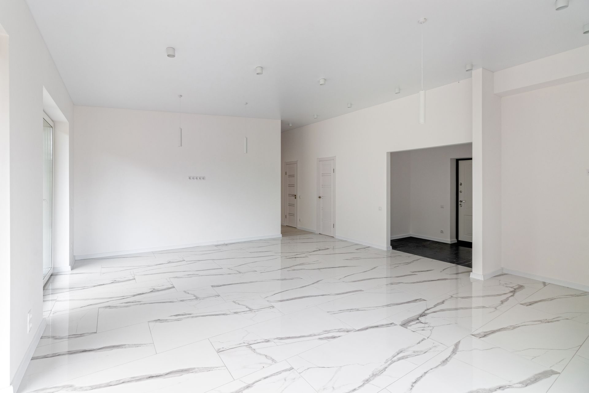 Bright empty white room with marble-pattern tile floor and large windows