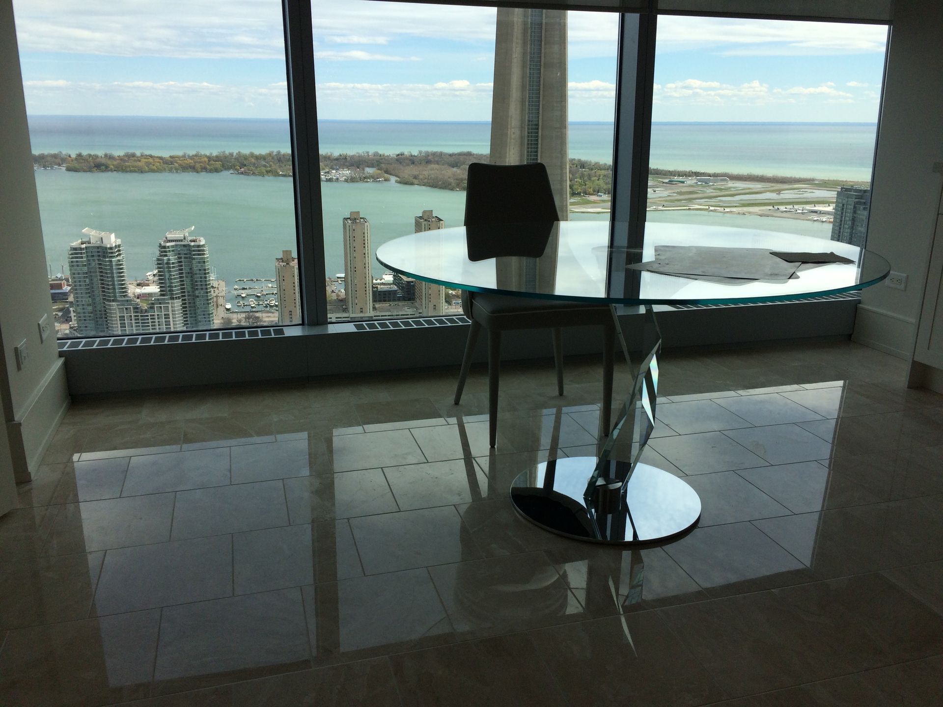 Modern room with glass table and chair overlooking a coastal city and bay through large windows