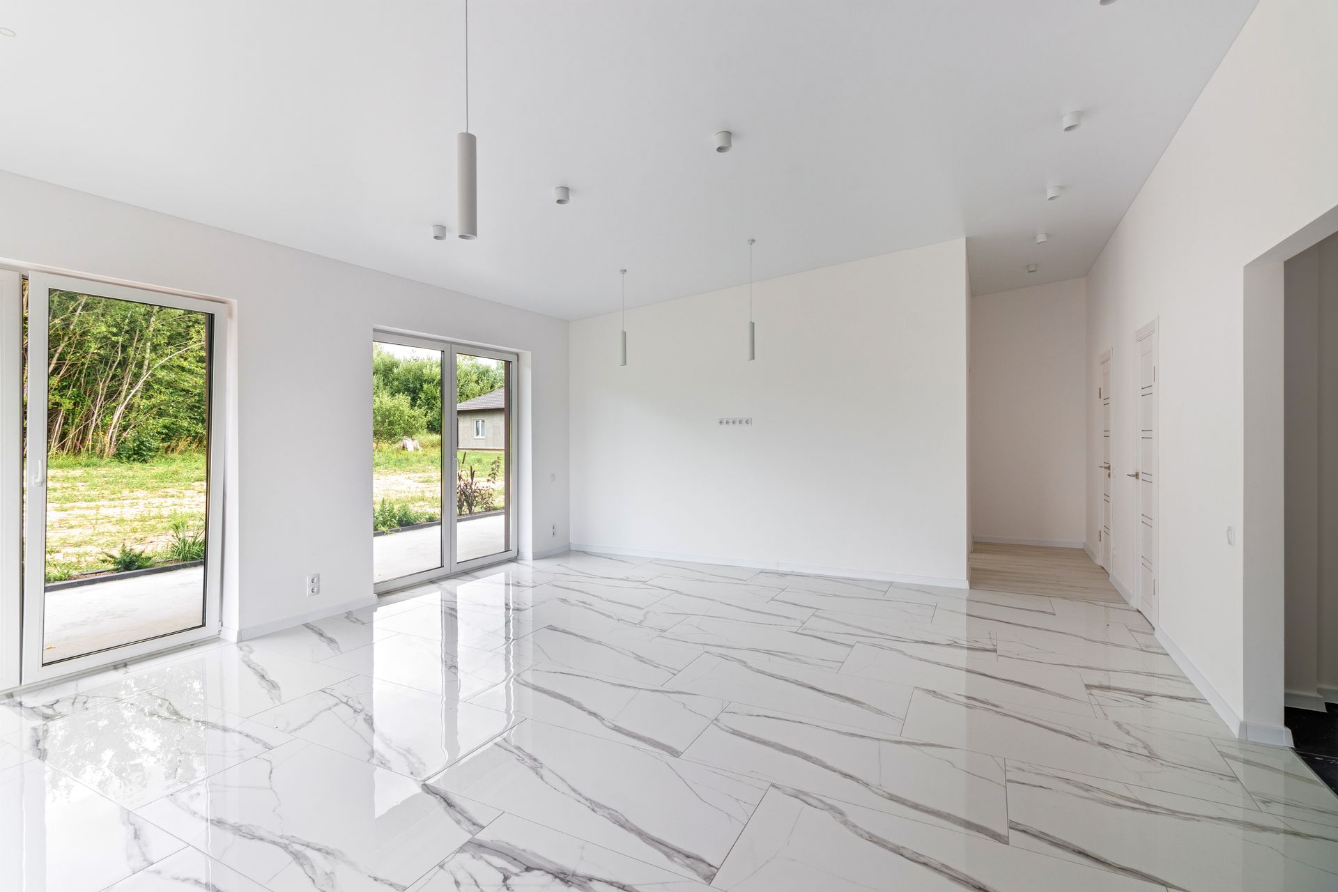 Bright empty modern room with white marble floors, large windows, and minimal recessed lighting