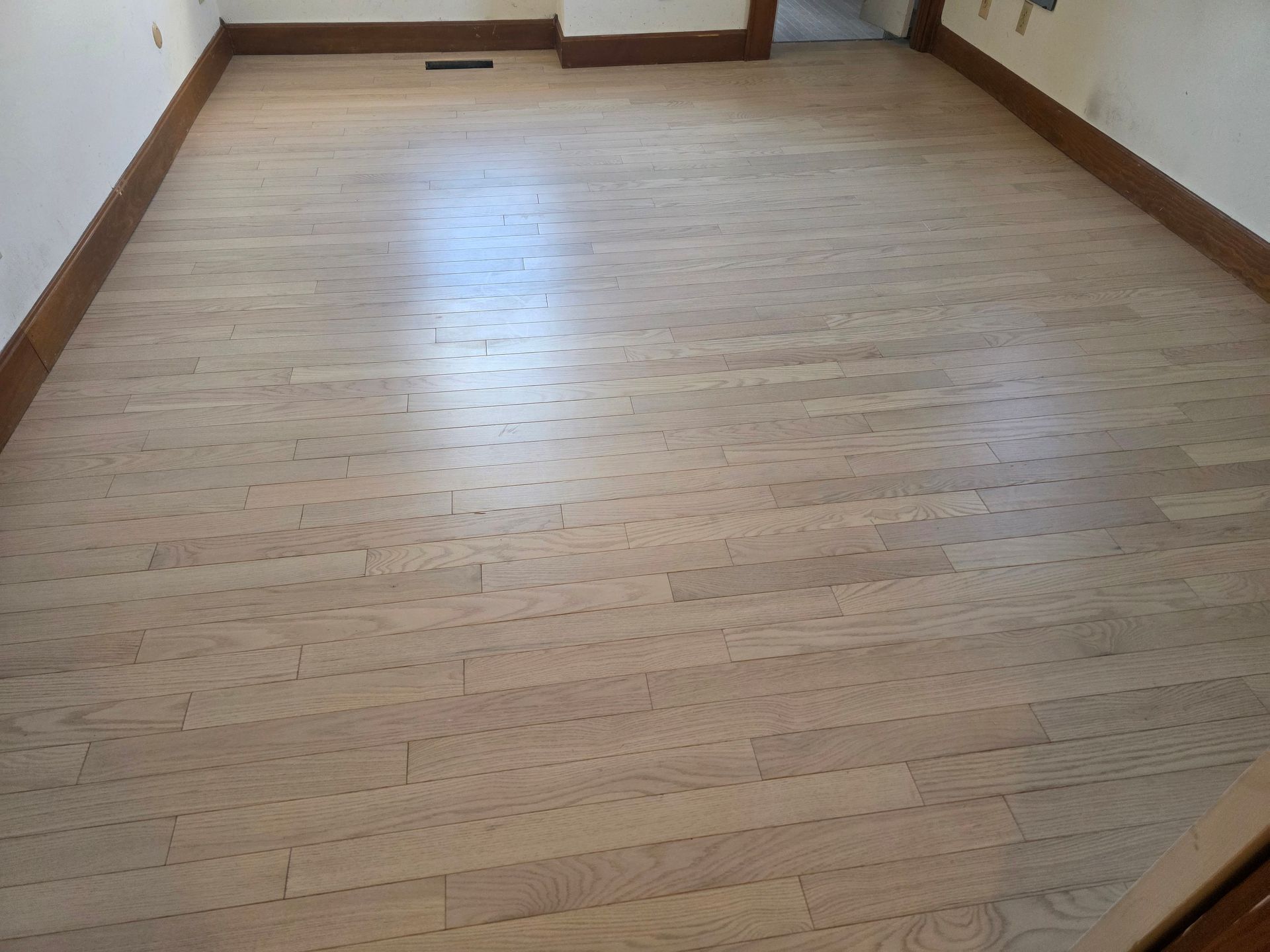 Empty room with light wood floor and white walls, viewed from the doorway