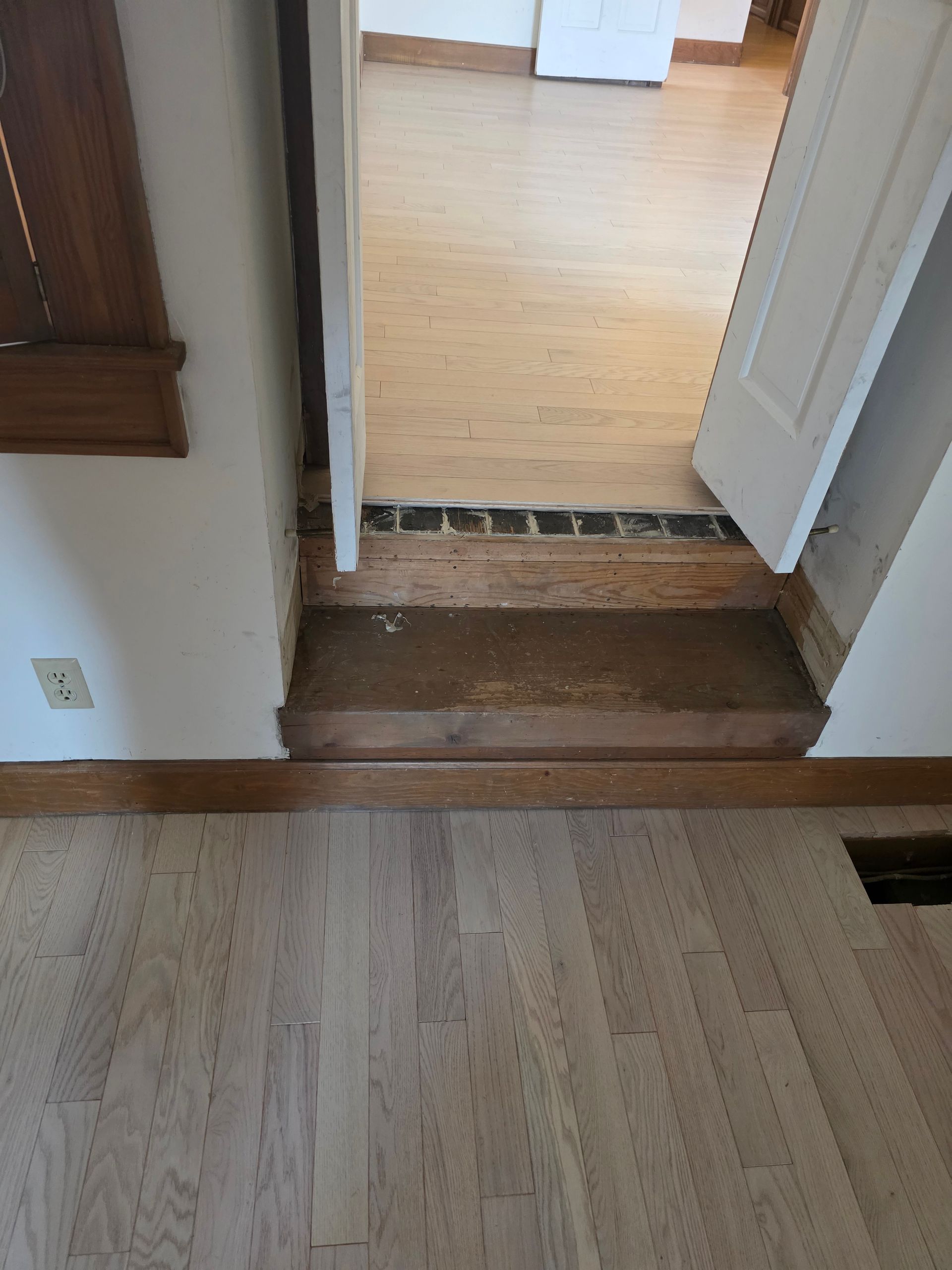 Interior doorway with a small step up and threshold between two wood-floored rooms