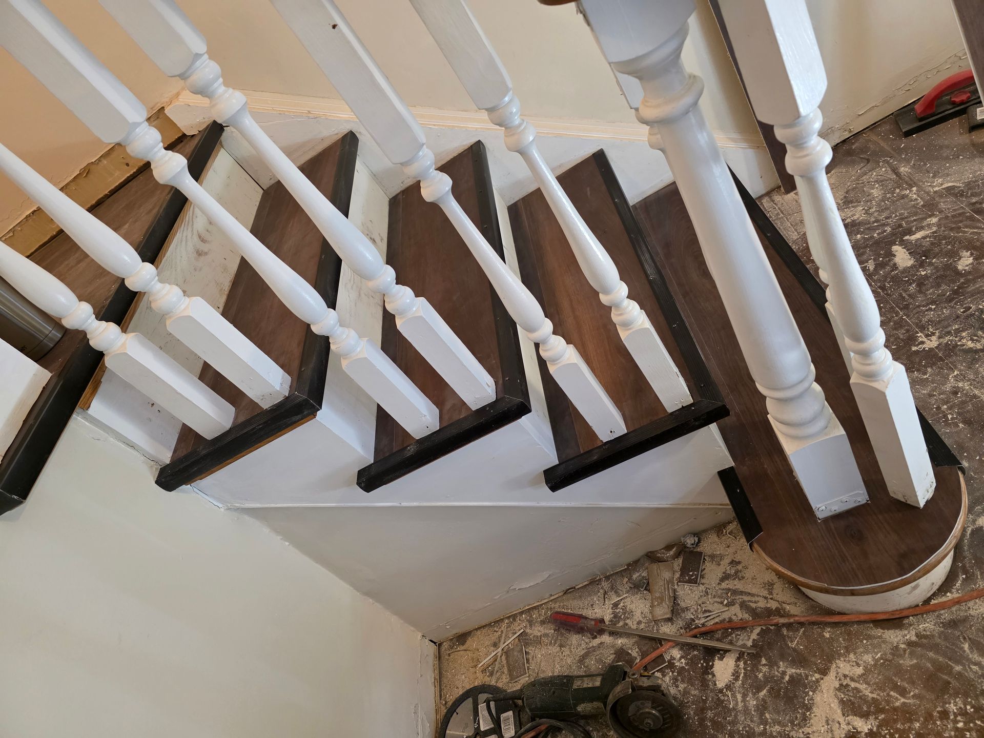 Indoor staircase with white balusters, dark wooden steps, and a bare floor below