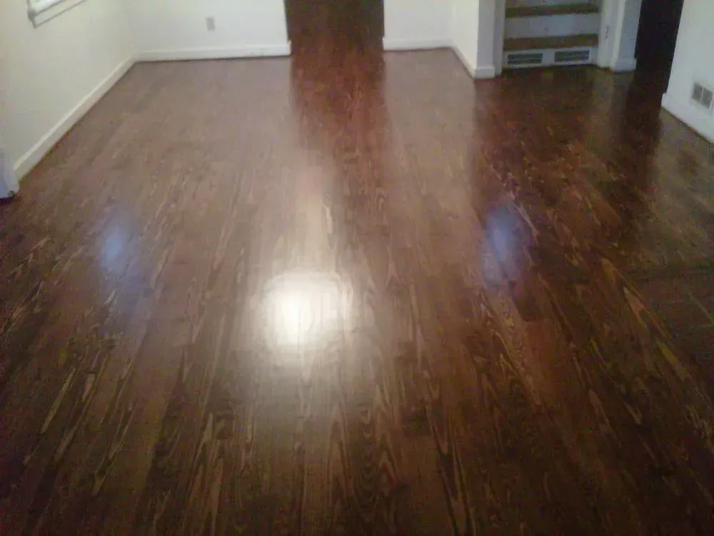 Empty room with glossy dark hardwood floors and white walls