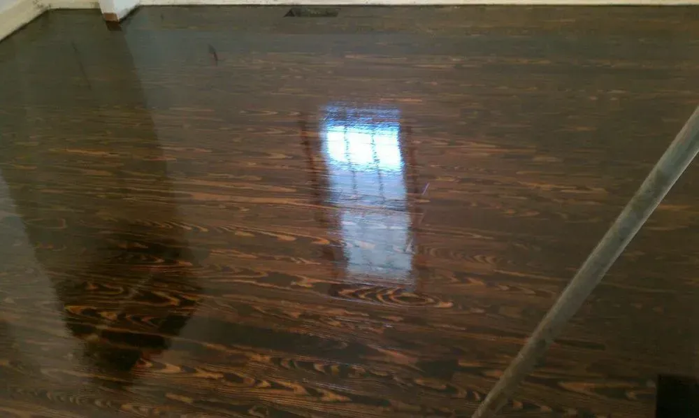 Dark hardwood floor with a bright window reflection and a shadow on the left side.