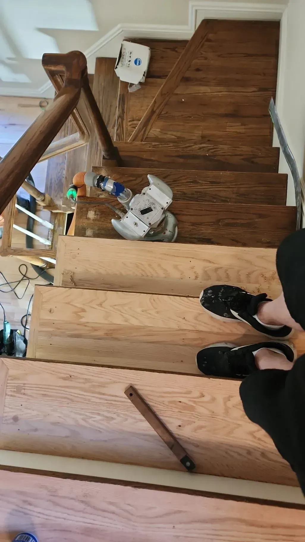 Staircase with wooden steps and a person’s black shoes visible at the bottom