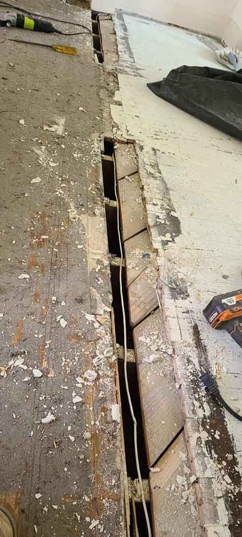 Damaged sidewalk with a long open trench beside a curb and scattered debris