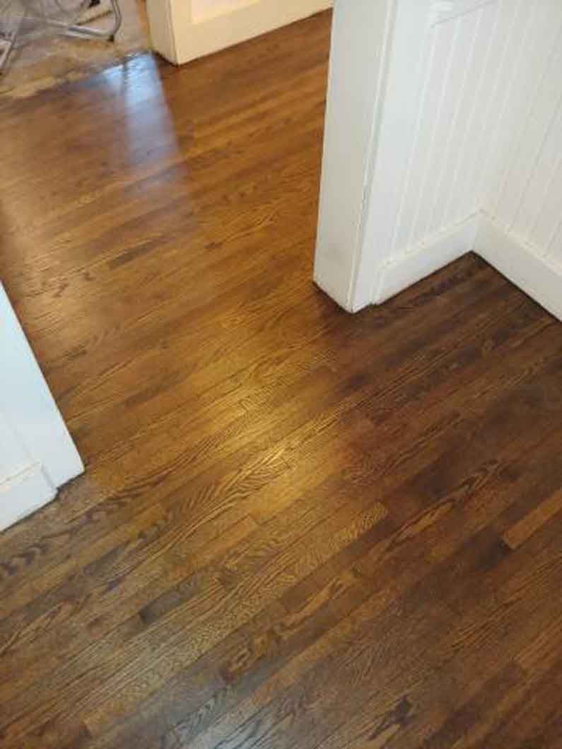 Wooden hallway floor with white doorways and trim, viewed from above