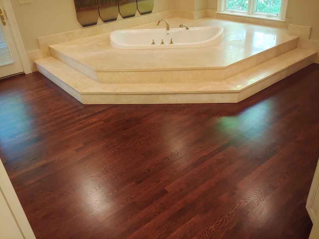 Luxury bathroom with a white corner soaking tub and dark hardwood floor