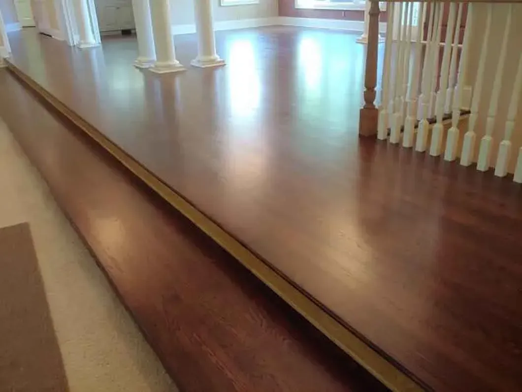 Wooden staircase landing and hallway with polished floors and white railings