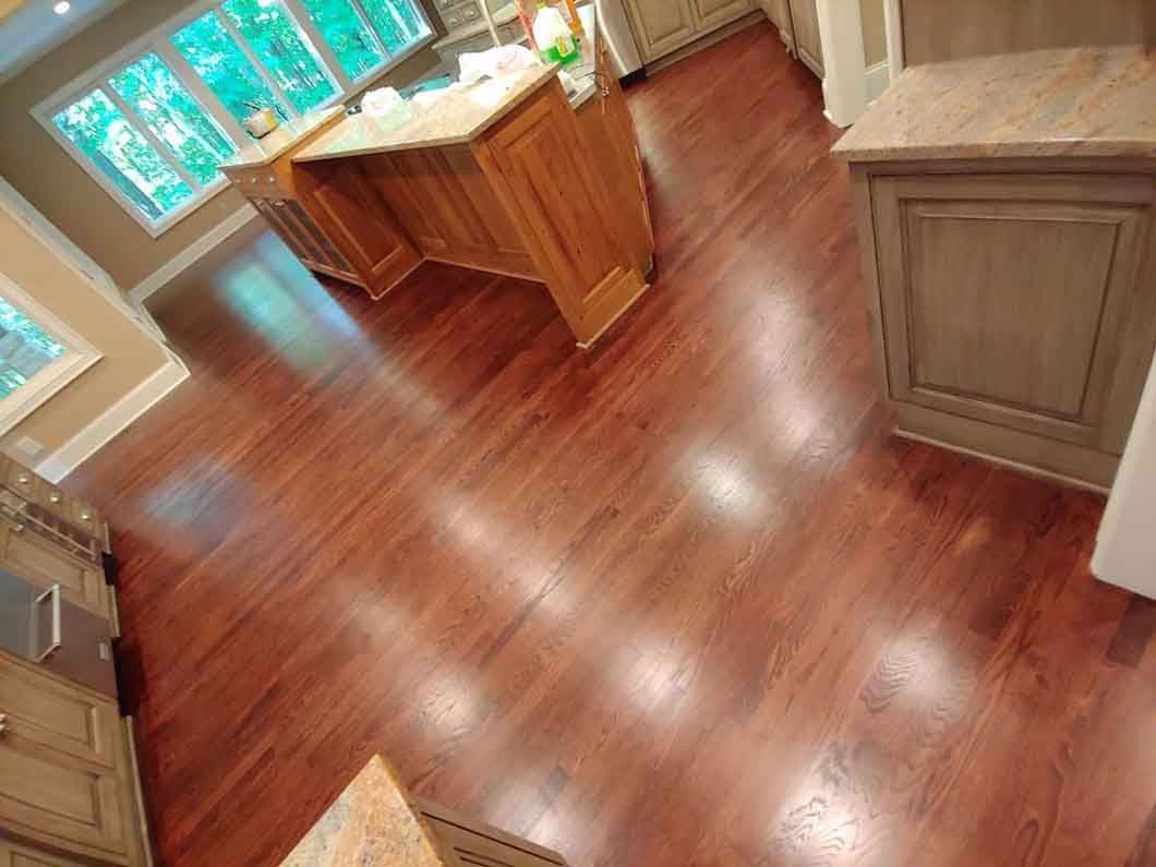 Empty kitchen with hardwood floors, wooden island, and bright windows.