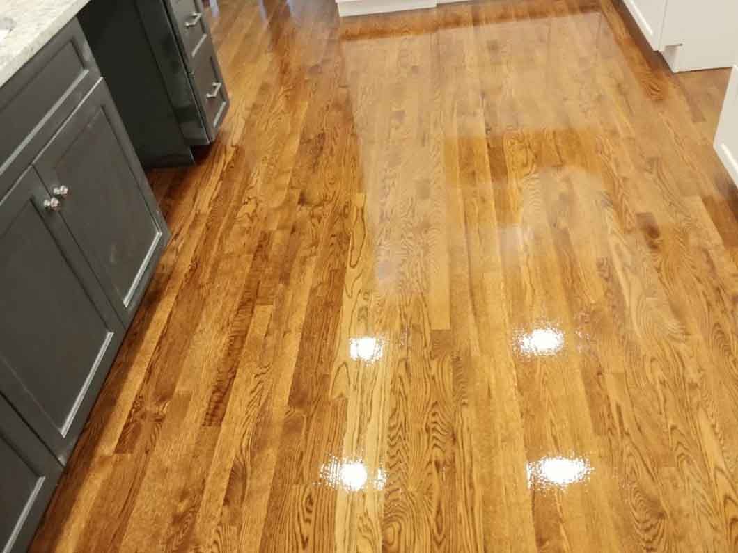Shiny hardwood kitchen floor with gray cabinets along the left side.