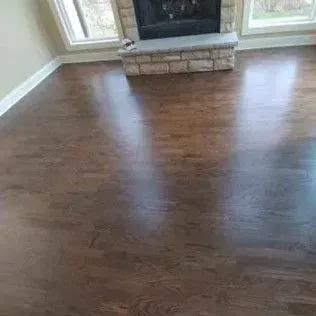 Empty living room with dark hardwood floors and a stone fireplace hearth