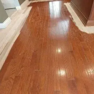 Shiny hardwood hallway floor with white trim and wood-paneled walls