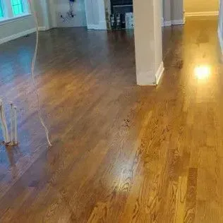 Empty hardwood-floored hallway with beige walls and doorways