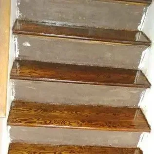 Wooden staircase with brown steps and beige risers viewed from below