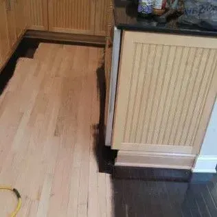 Kitchen floor with a long recessed section under a counter, showing unfinished wood flooring next to dark flooring.