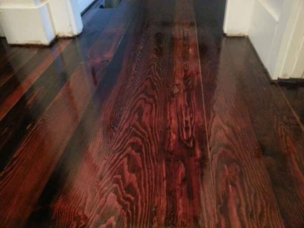Dark wood-patterned hallway floor with red and black tones, viewed from above