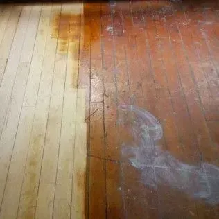 Wet wooden floor with a light-colored strip and a darker, water-stained section on the right.